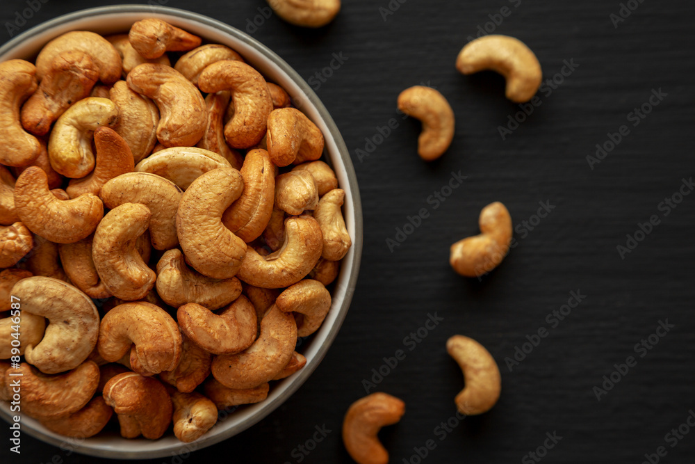 Fototapeta premium Roasted Organic Cashews in a Bowl on a black background, top view.
