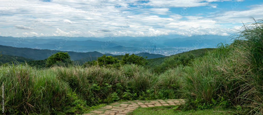 Naklejka premium Walking trails in the grasslands of Yangmingshan National Park, with the city of Taipei in the distant background, Taiwan