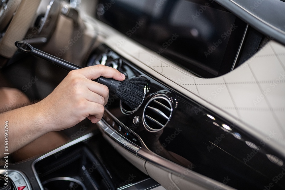 Detailing interior car dashboard using brush, ensuring thorough cleaning and high-quality finish. Focus on precision and cleanliness in professional auto detailing