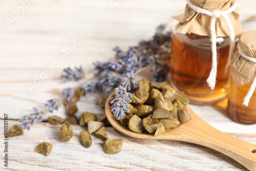 Natural honey tincture, lavender and propolis granules on white wooden table, closeup