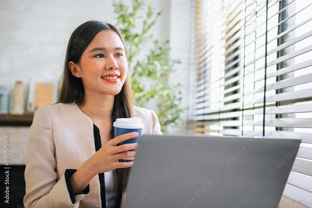woman is sitting at a desk with a laptop and a cup of coffee woman is sitting at a desk with a laptop and a cup of coffee