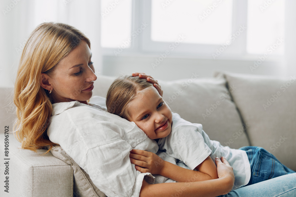 Mother and daughter bonding on a cozy living room couch in front of a sunlit window, sharing a warm moment Mother and daughter bonding on a cozy living room couch in front of a sunlit window, sharing a warm moment