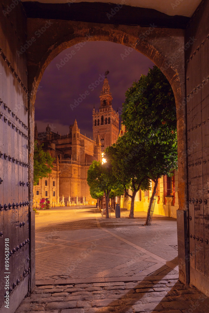 Naklejka premium Night view of Giralda Tower framed by an archway in Seville, Spain