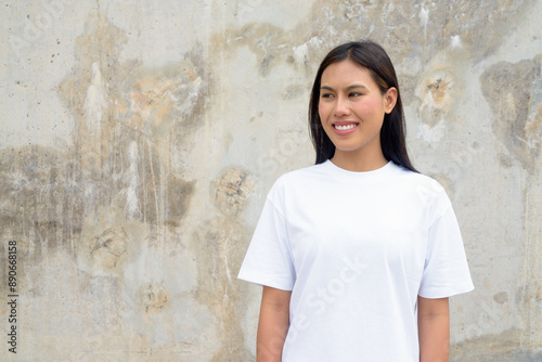 Young Thai Woman Smiling Outdoors Against Wall Background