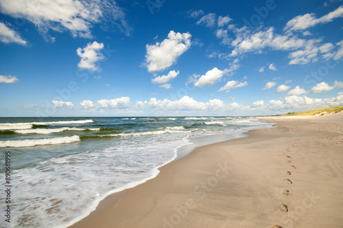 Empty, sandy beach and sea waves by sunny day