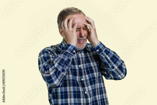 Portrait of senior man holds his head with both hands because of headache or disappontment. Isolated on white. photo