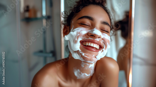 Young woman laughing with shaving foam on face in bathroom