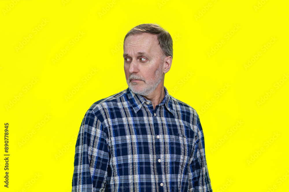 Portrait of serious caucasian man is looking back. Isolated on yellow. Portrait of serious caucasian man is looking back. Isolated on yellow.