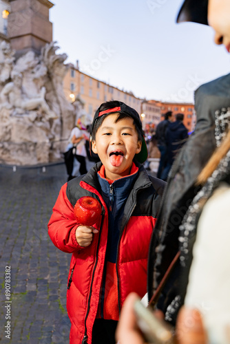 Young boy enjoying a candied apple at a busy Christmas market photo