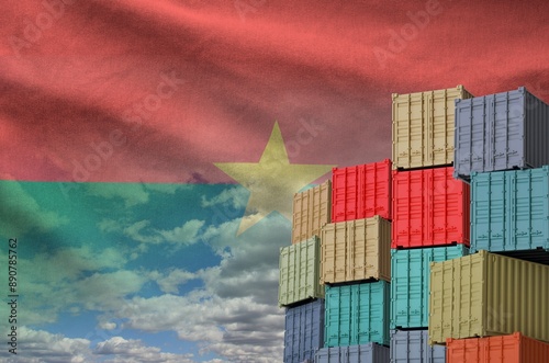 Burkina Faso flag and big stack of shipping cargo containers in docks with sky background close up photo