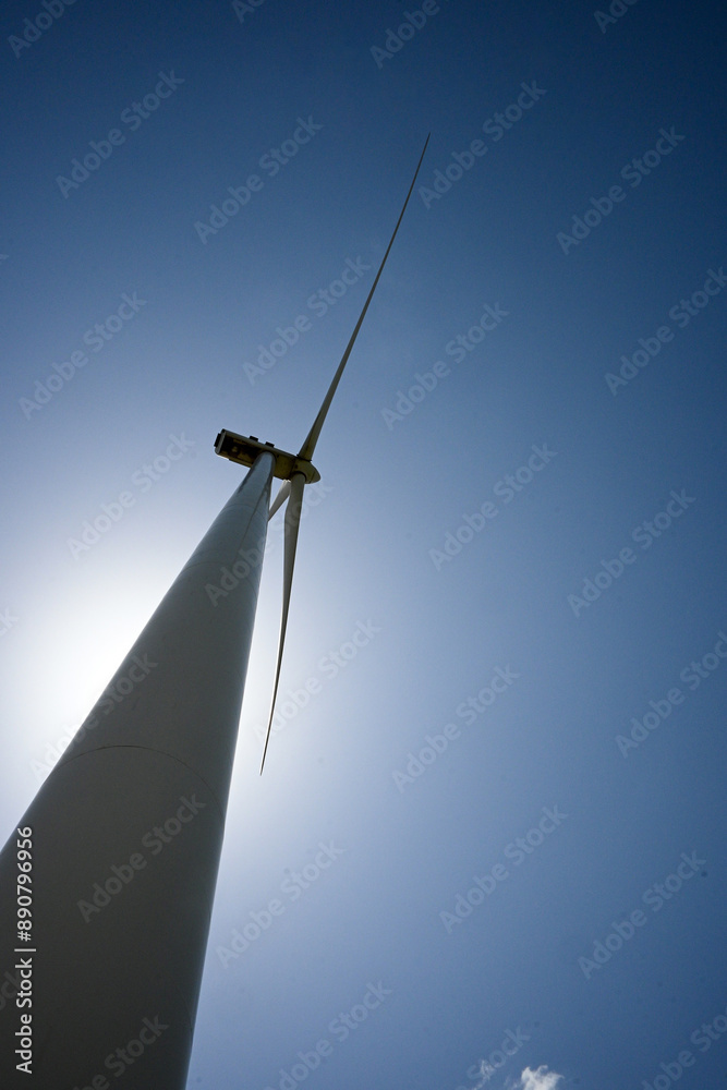 Wind turbine is standing tall against a blue sky, generating clean and renewable energy