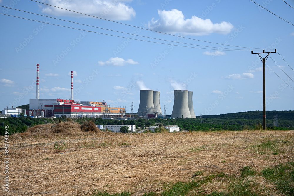 Large nuclear power plant cooling towers are standing tall in the distance on a sunny day Large nuclear power plant cooling towers are standing tall in the distance on a sunny day