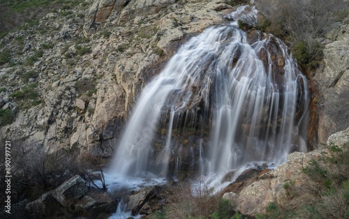 A stunning waterfall cascading down rocky cliffs in a mountainous landscape