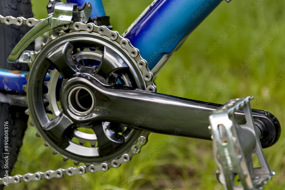 mountain bike double crankset detail with pedal (new shiny high end gray grey gunmetal) chain front derailleur on blue frame bicycle cycling biking riding gear components mountain bike double crankset detail with pedal (new shiny high end gray grey gunmetal) chain front derailleur on blue frame bicycle cycling biking riding gear components