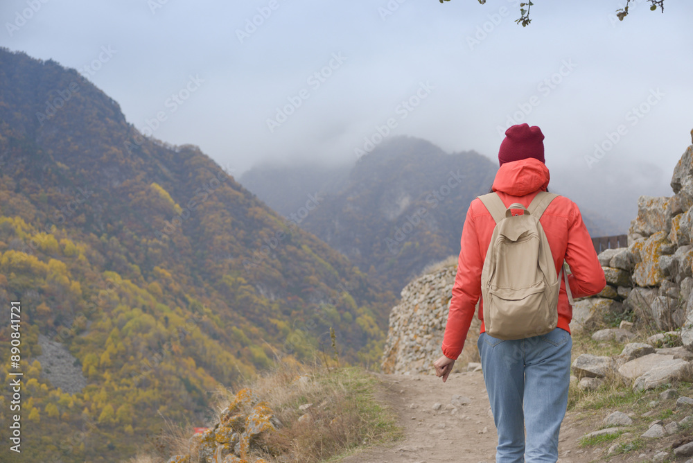 A free woman traveler walks along paths in the mountains on a foggy autumn day. Adventure travel and success concept