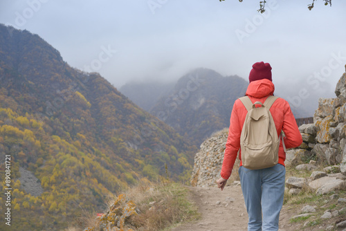 A free woman traveler walks along paths in the mountains on a foggy autumn day. Adventure travel and success concept