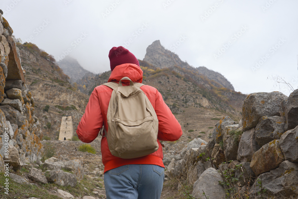 A free woman traveler walks along paths in the mountains on a foggy autumn day. Adventure travel and success concept