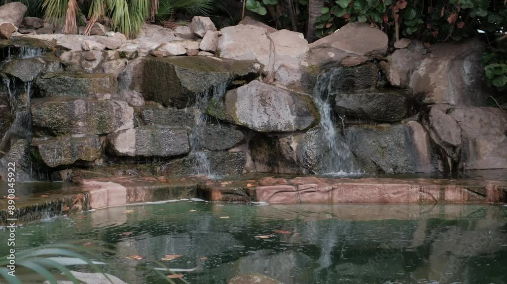 SANTA CRUZ DE TENERIFE, SPAIN - MARCH 3, 2024: Water cascading over rocks into a small pond at the Palmetum in Santa Cruz, Tenerife. SANTA CRUZ DE TENERIFE, SPAIN - MARCH 3, 2024: Water cascading over rocks into a small pond at the Palmetum in Santa Cruz, Tenerife.