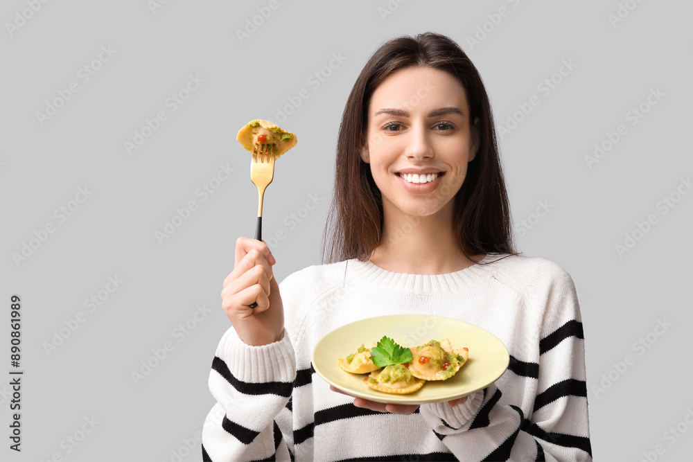 Beautiful young woman with plate of tasty ravioli on grey background Beautiful young woman with plate of tasty ravioli on grey background