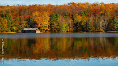 Log cabin by the lake in the woods, water reflections in fall, secluded lake house getaway