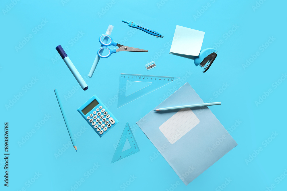 Books with different school stationery flying on blue background Books with different school stationery flying on blue background
