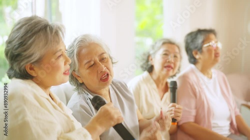Group of Happy Asian senior women friends singing karaoke with dancing together in living room. Elderly retired people enjoy and fun indoor lifestyle spending time together with home entertainment.
