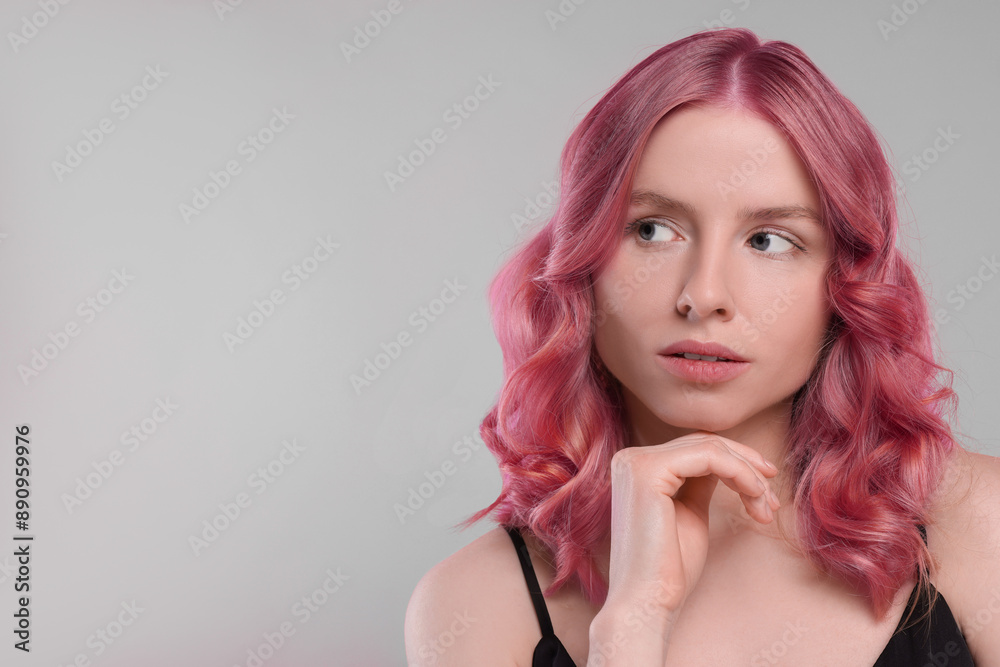 Pretty young woman with pink hair on grey background, space for text Pretty young woman with pink hair on grey background, space for text