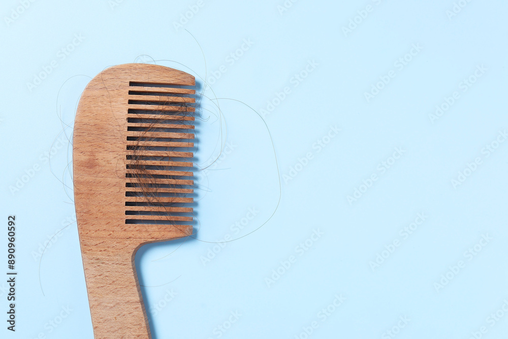 Wooden comb with lost hair on light blue background, top view. Space for text Wooden comb with lost hair on light blue background, top view. Space for text