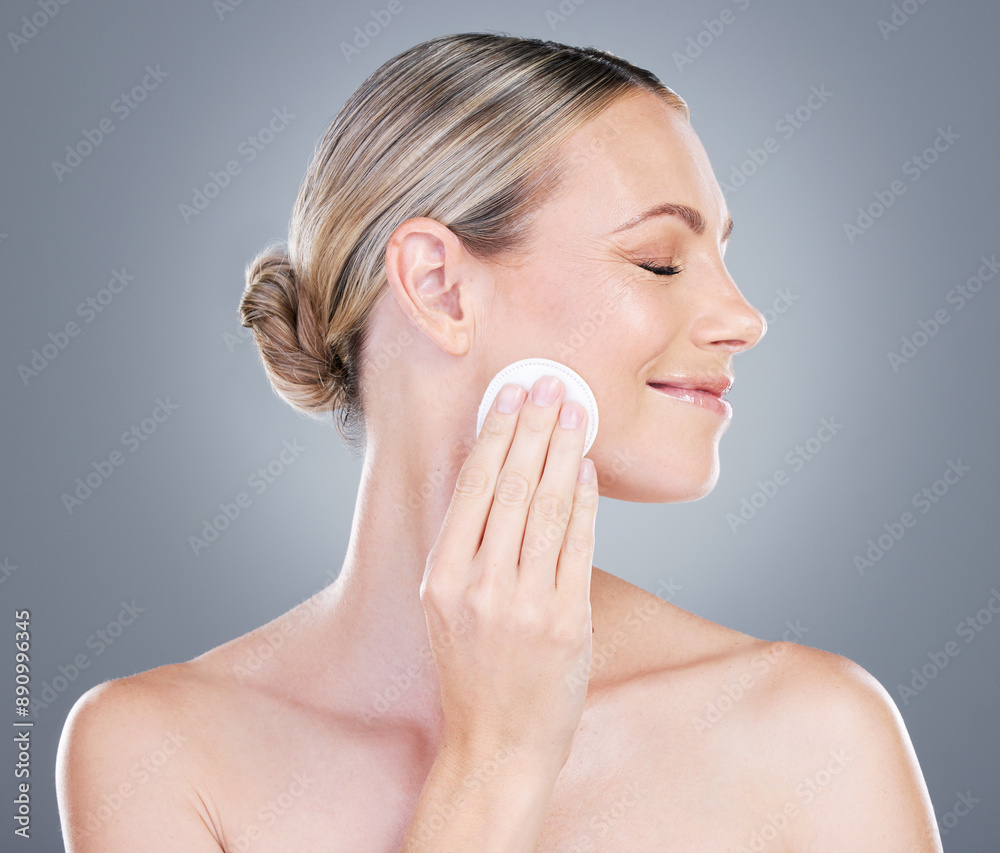 Happy woman, cotton pad and cosmetics with makeup for foundation, blush or removal on a gray studio background. Female person or model with smile or patch for applying beauty or facial treatment Happy woman, cotton pad and cosmetics with makeup for foundation, blush or removal on a gray studio background. Female person or model with smile or patch for applying beauty or facial treatment