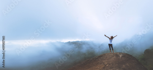 Young woman exercises yoga in the mountains. Asian woman travel nature. Travel relax exercises yoga touch natural fog on mountain peak.