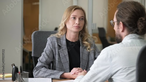 Confident businesswoman listen and having a serious conversation to her colleague in front of her desk. Man sitting an making a hand gestures.