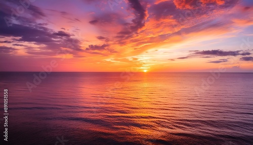 Fiery orange sun dips below the horizon, casting long reflections across the rippling ocean waves