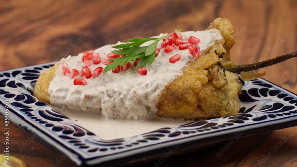 Chiles en nogada, bathed in walnut sauce, pomegranate seeds and a parsley leaf, served on a talavera plate, Haute cuisine of Mexico Travel shot left