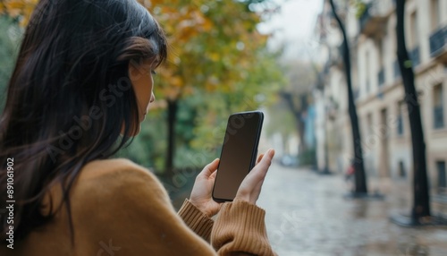 Woman Using Smartphone on City Street in Autumn