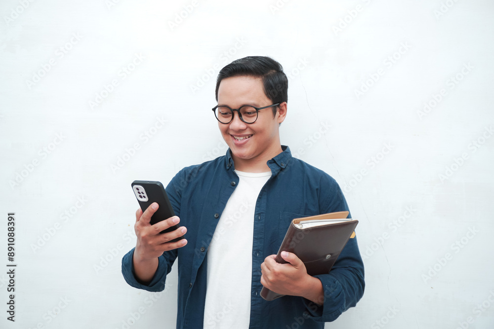 Young Asian man holding books and phone smiling happy and positive. Isolated on white background Young Asian man holding books and phone smiling happy and positive. Isolated on white background