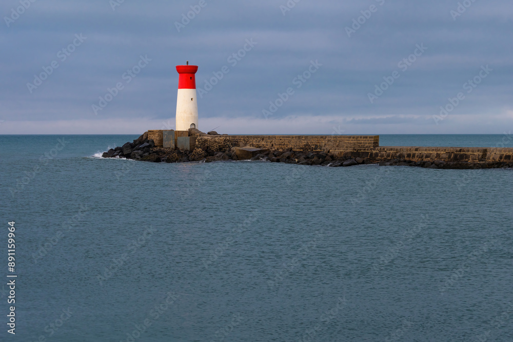 A lighthouse is on a rocky shoreline A lighthouse is on a rocky shoreline