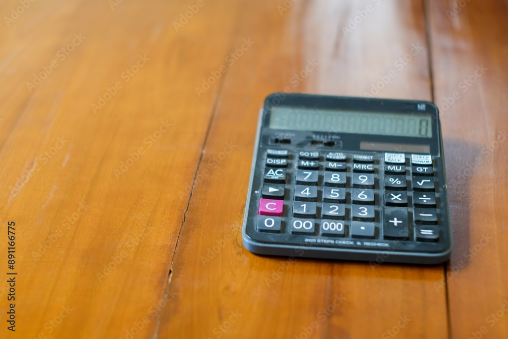 A black Calculator on a wooden floor background. Top view. Copy space, cost, tax or investment calculation. A black Calculator on a wooden floor background. Top view. Copy space, cost, tax or investment calculation.