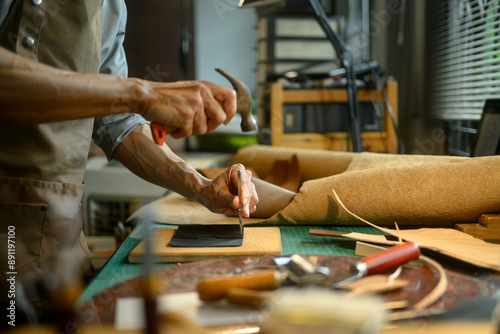 Professional craftsman using a hammer and other tools to shape and detail the leather piece photo