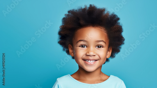 Portrait of smiling cute African American child girl with short haircut problem, light blue background, banner.