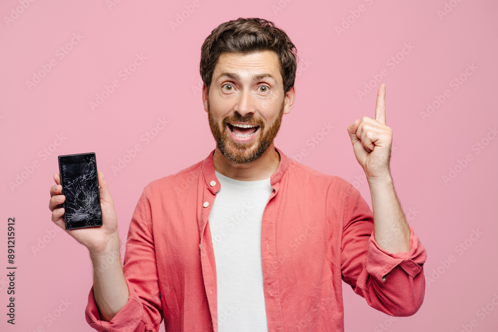 © Maria Vitkovska - Happy young man showing broken mobile phone holding finger up, looking at camera © Maria Vitkovska - Happy young man showing broken mobile phone holding finger up, looking at camera