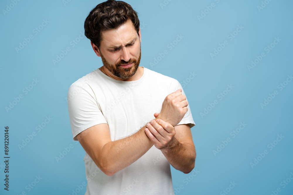 Unhappy man suffering from pain in hand over blue background Unhappy man suffering from pain in hand over blue background