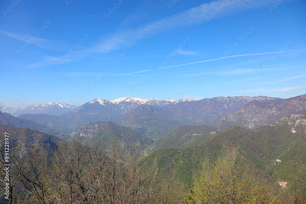 Breathtaking alpine panorama in northern Italy with mountain range in background and blue sky Breathtaking alpine panorama in northern Italy with mountain range in background and blue sky
