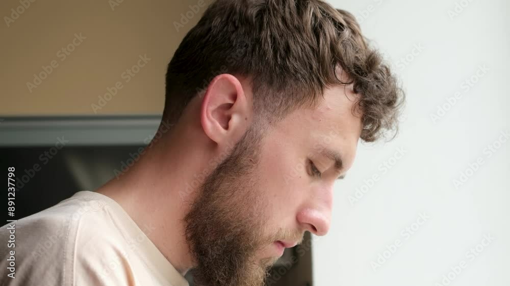 Portrait of a young bearded man washing cutlery in the kitchen. Close-up, side view. Portrait of a young bearded man washing cutlery in the kitchen. Close-up, side view.