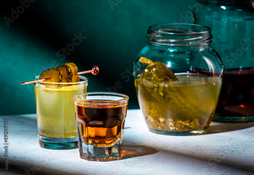 Alcoholic cocktail drink from cucumber pickle and whiskey in shot glasses. Dark green background photo