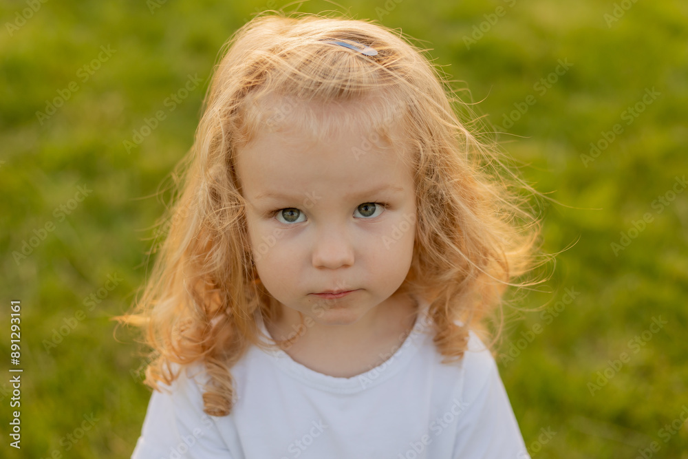 Cute blonde kid with curly hair walks on the lawn with soap bubbles in summer Cute blonde kid with curly hair walks on the lawn with soap bubbles in summer