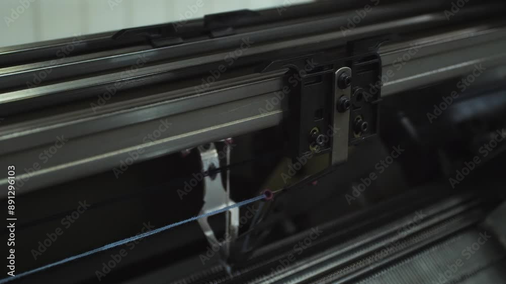 Close-up tracking shot of automatic weaving machine producing fabric in textile factory