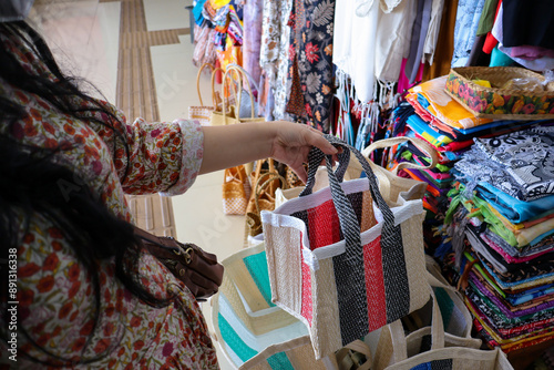 A tourist explores Sukawati Art Market in Bali, searching for unique bag. Browsing vibrant stalls filled with traditional designs and handcrafted materials. Enjoying the cultural shopping experience. photo