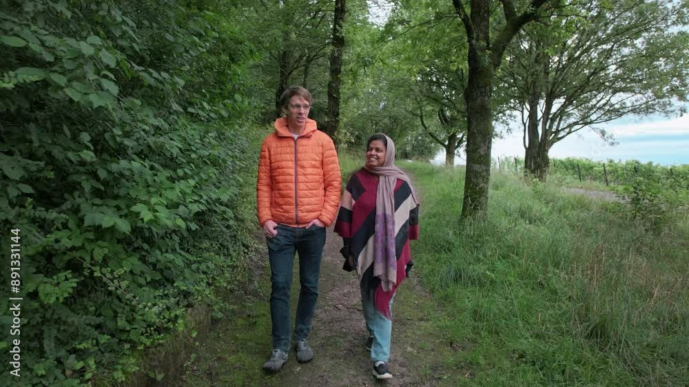 Two friends or a couple enjoy a relaxed walk in a park and have a happy conversation. Lifestyle slow motion footage Two friends or a couple enjoy a relaxed walk in a park and have a happy conversation. Lifestyle slow motion footage