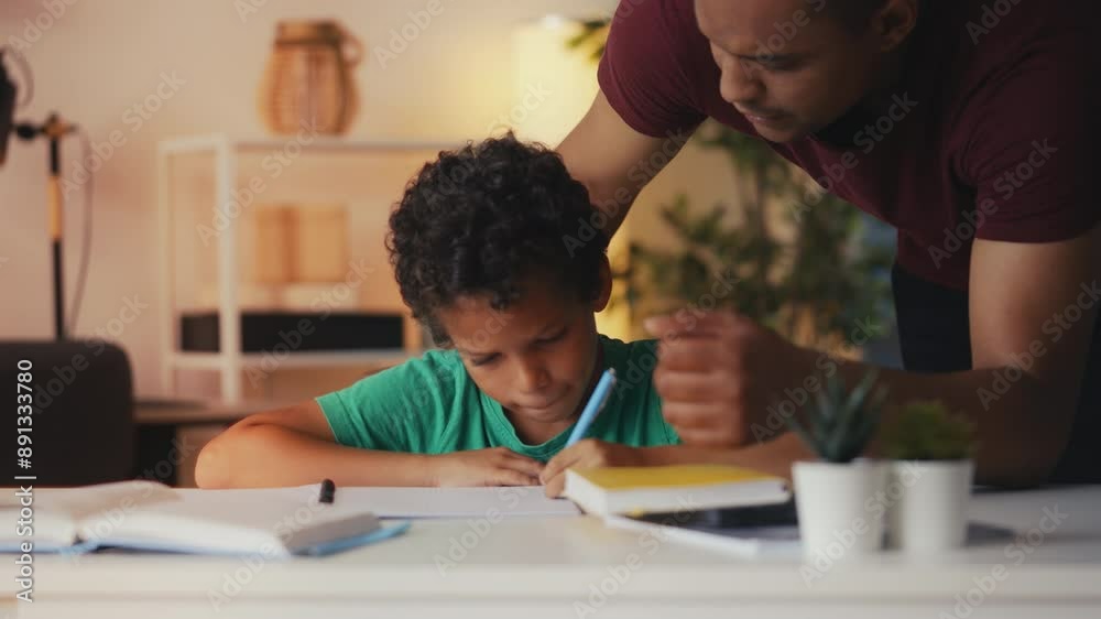 Strict dad losing his patience and talking harshly to little son doing homework Strict dad losing his patience and talking harshly to little son doing homework