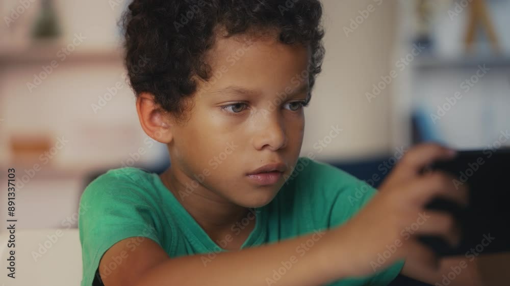 Gadget-addicted little boy playing games on smartphone, neglecting homework Gadget-addicted little boy playing games on smartphone, neglecting homework